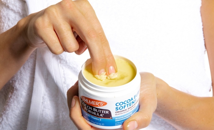 dipping fingers in palmers cocoa butter solid jar to show texture